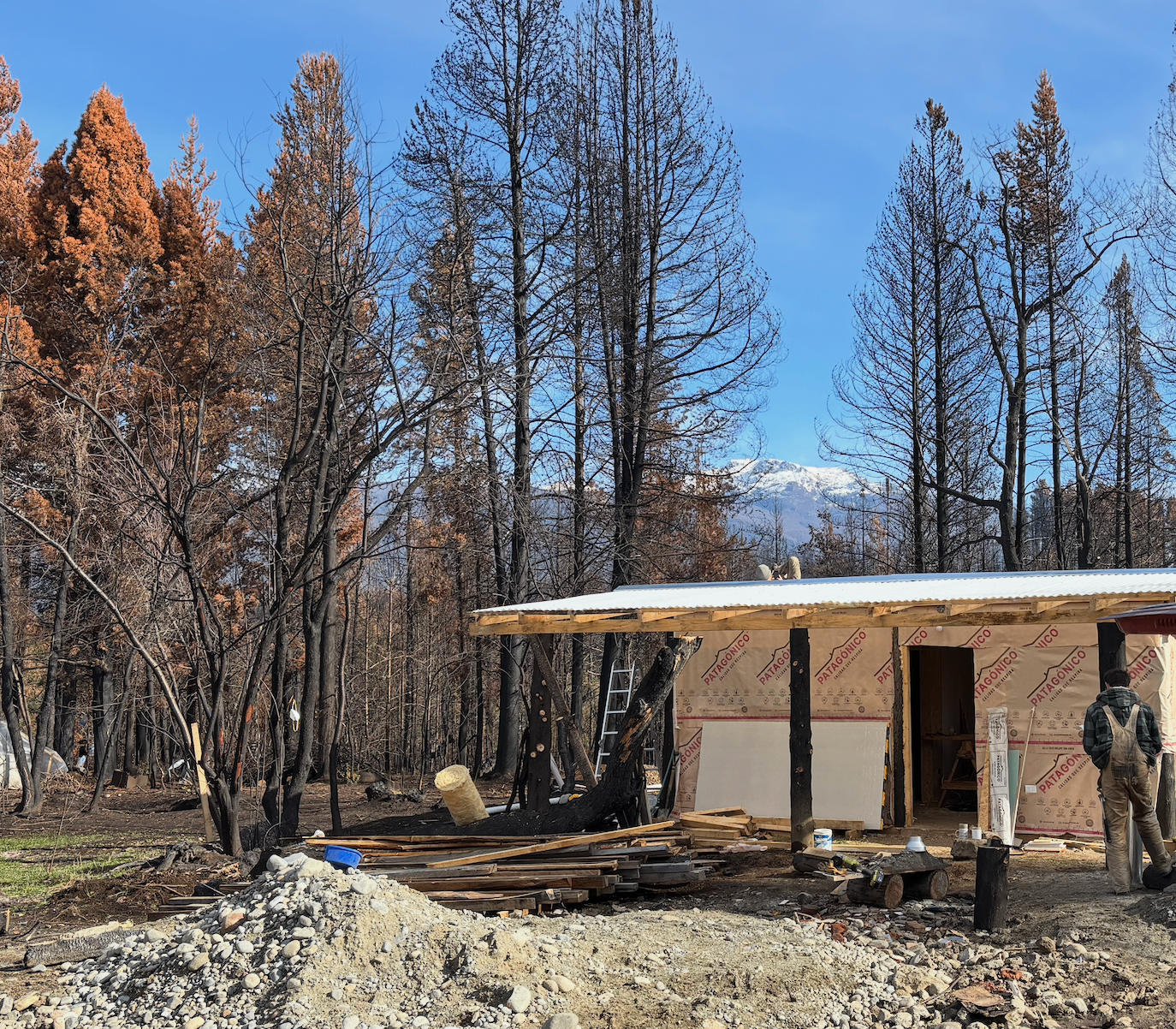 Cabin under construction with wooden siding and carport